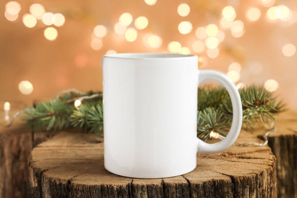 istock White cup on a wooden background with fir branches close-up front view. Mockup for design, template for logo with copy space. 1354822711