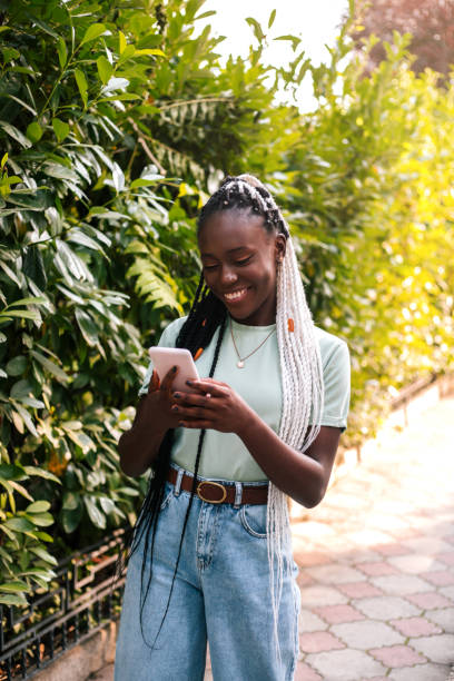 istock Beautiful black woman using smartphone at street. 1354823653