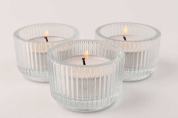 istock Burning tea candles in a glass holder, isolated on white. Space for text 1354824272