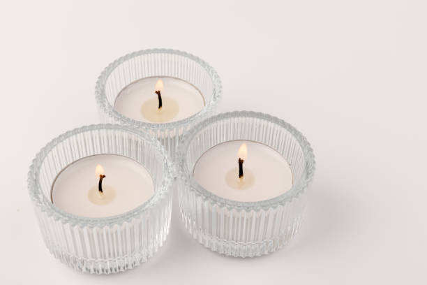istock Burning tea candles in a glass holder, isolated on white. Space for text 1354824273