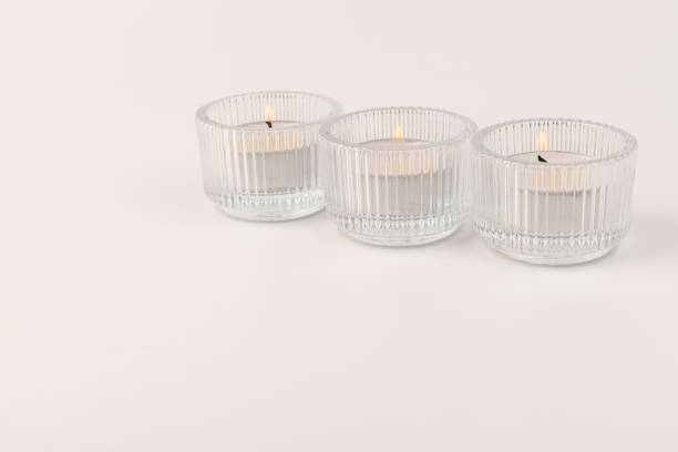 istock Burning tea candles in a glass holder, isolated on white. Space for text 1354824282