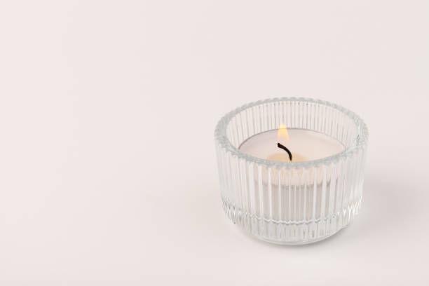 istock Burning tea candles in a glass holder, isolated on white. Space for text 1354824289