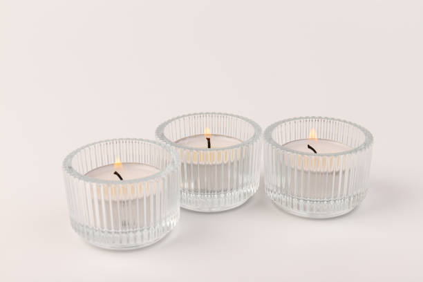 istock Burning tea candles in a glass holder, isolated on white. Space for text 1354824352