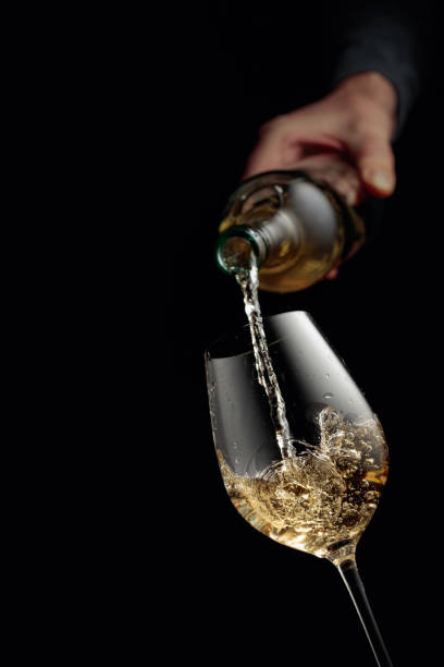 istock Pouring white wine in a glass goblet. 1354824995