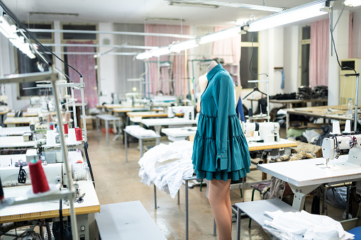 Mannequin with a green dress on it in a professional atelier