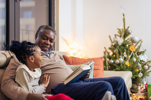 Grandfather and granddaughter reading book. Christmas time