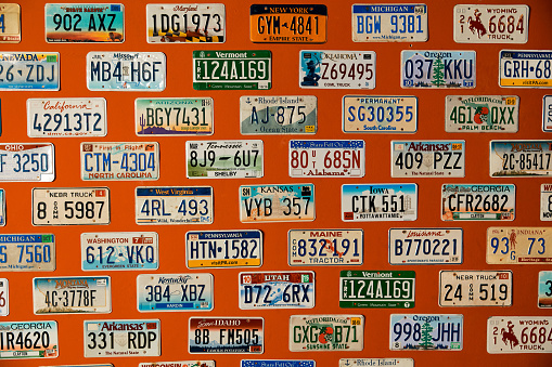 American license plates hang on an orange wall. High quality photo