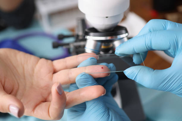 Laboratory worker taking blood from female finger for investigation Close-up of laboratory worker taking blood from female finger for investigation. Modern microscope on table in lab. Medicine, chemistry, science concept blood typing stock pictures, royalty-free photos & images