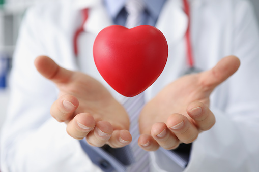 Trabajador médico arroja corazón de plástico rojo y lo atrapa en las palmas de las manos photo