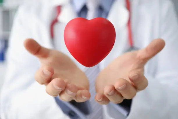 Photo of Medical worker throw red plastic heart and catch it in palms