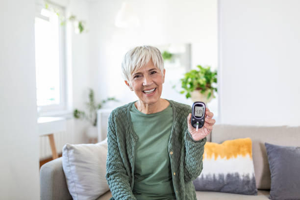 blood sugar testing at home. checking blood sugar level at home. diabetic checking blood sugar levels. woman checking blood sugar level by glucometer and test stripe at home - diabetes home interior blood sugar test healthcare and medicine imagens e fotografias de stock