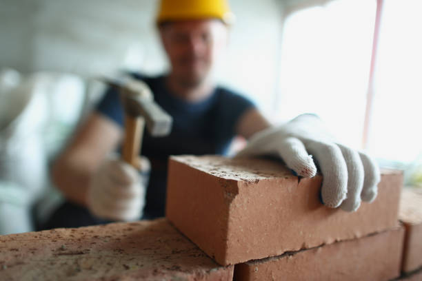 istock Skilled foreman in hardhat use hammer equipment to put blocks on unfinished structure 1354828968