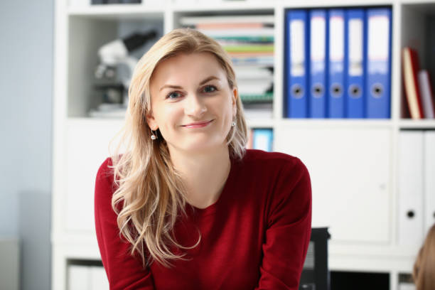 Beautiful young woman office worker posing in personal cabinet Portrait of beautiful young woman office worker posing in personal cabinet. Smiling female in trendy red pullover. Work, career, business, modeling concept file clerk stock pictures, royalty-free photos & images