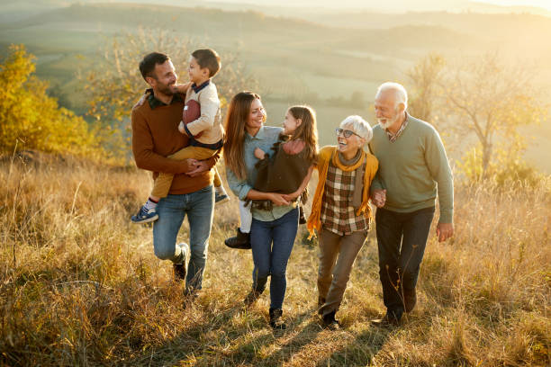 Happy multi-generation family talking while taking a walk on a hill. Happy extended family communicating while walking in autumn day on a hill. three generation family stock pictures, royalty-free photos & images
