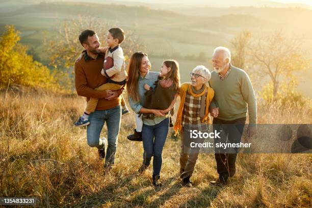 Happy Multigeneration Family Talking While Taking A Walk On A Hill Stock Photo - Download Image Now