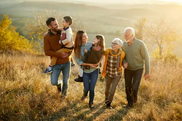 Happy extended family communicating while walking in autumn day on a hill.