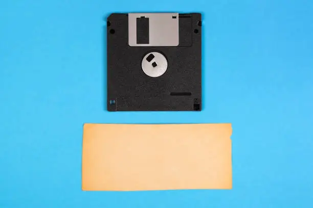 Floppy Disk Drive with a Blank Old Paper on the Blue Paper Background closeup
