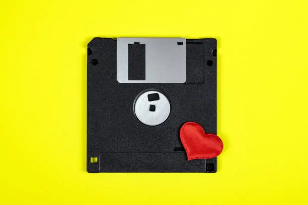 Floppy Disk Drive with a Red Heart on the Yellow Paper Background closeup