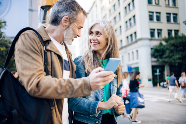 istock Happy mature couple on vacation walking and using smartphone 1354839416
