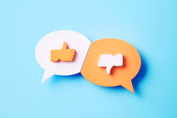 like and dislike concept - white and pink speech bubble pair with like and dislike symbols sitting over blue background - thumbs up human thumb human hand conflict imagens e fotografias de stock