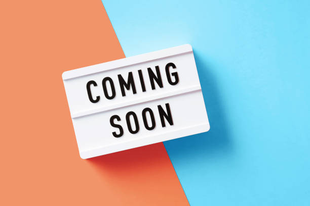 Coming Soon written white lightbox sitting on pink and blue background. Horizontal composition with copy space. Coming soon sign concept.