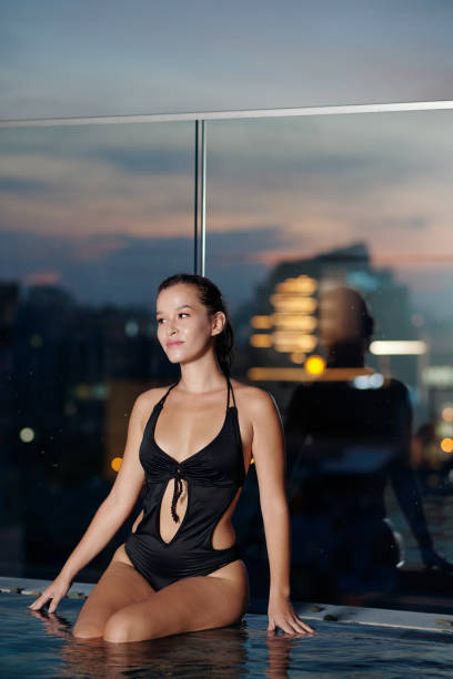 istock Young Woman Sitting on Swimming Pool Edge 1354841291