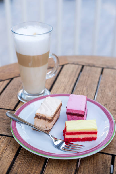istock Latte coffee in a glass mug and a cake is on the table in a cafe. 1354841309