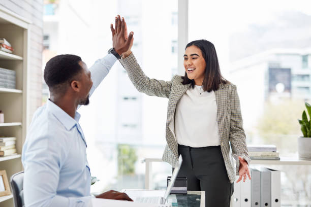 tiro de dois empresários dando um ao outro um high five em um escritório - young men adult working gesturing - fotografias e filmes do acervo