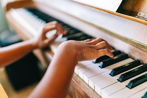 Musical education. Happy black girl playing the piano at home