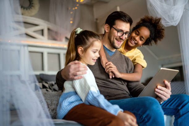 istock Multiethnic children and father having fun, playing on tablet at home 1354842148