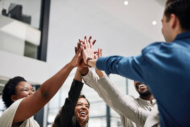 shot of a group of businesspeople giving each other a high five in an office - excitement business person ecstatic passion imagens e fotografias de stock