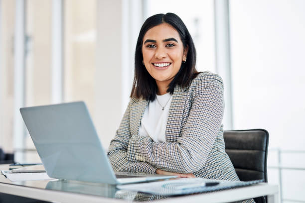 portrait of a young businesswoman working on a laptop in an office - computeren fotos stockfoto's en -beelden