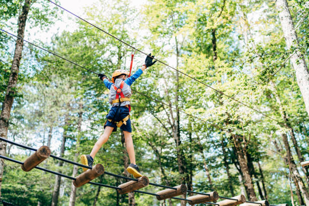 istock Boy walking on the agility bridge holding on to the ropes 1354844310