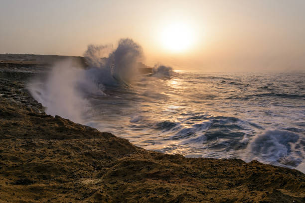 long exposure shot from the waves in the beach of Chabahar at sunset located in baluchistan, iran. waves hitting the rocks over oman sea. beach with cliff and rocks.