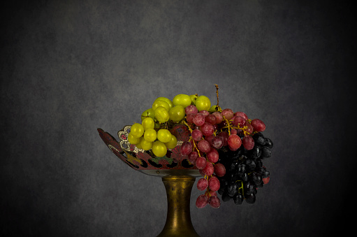 Portrait of different kind of grapes on fruit tray against gray background