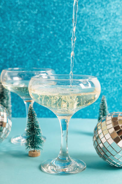 Christmas minimal festive background with disco ball, toy tree, glasses of champagne. Abstract glitter Christmas and New Year color background blue ai aqua. Bright sparkling wallpaper texture. stock photo