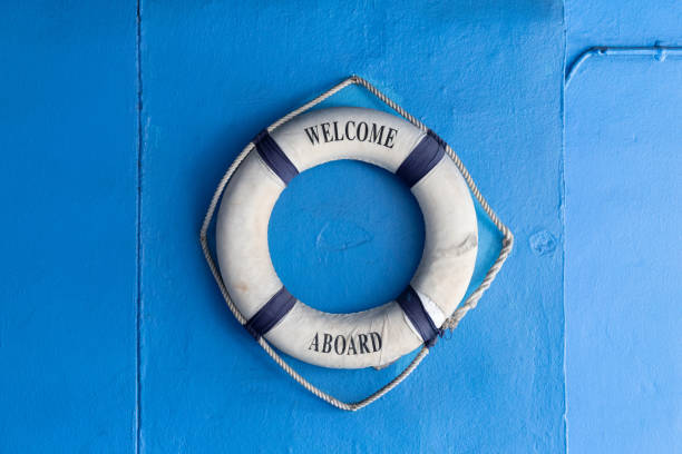 istock Lifebuoy with Welcome aboard phrase hang on blue concrete background. 1354850093