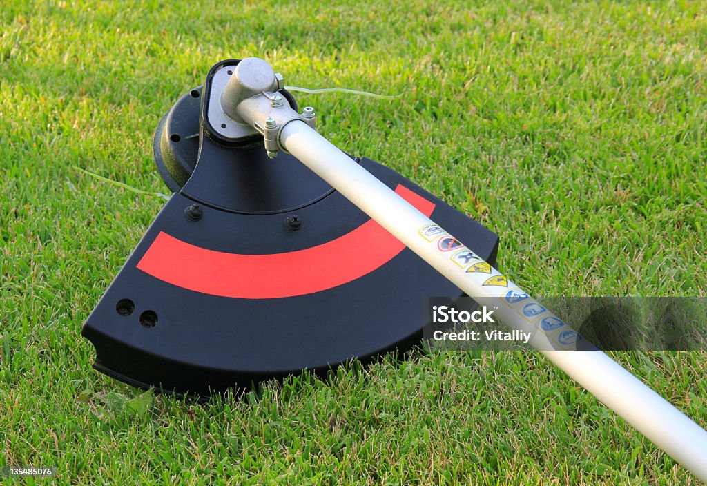 Weed trimmer in red and black on the grass Part of weed trimmer, close-up Cutting Stock Photo