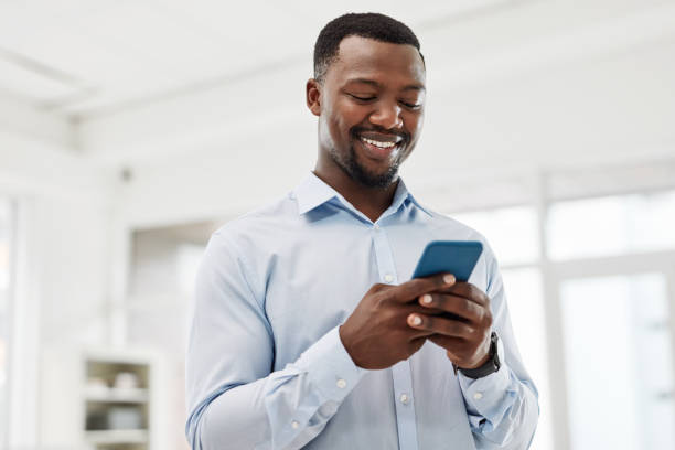 istock Low angle shot of a young businessman using a cellphone in an office 1354851483