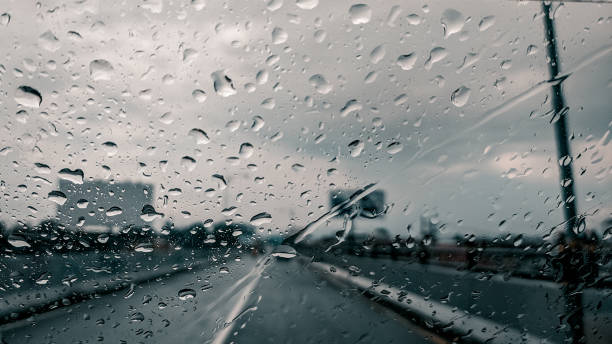 istock Raindrops on the windshield of a car on asphalt road background 1354852504