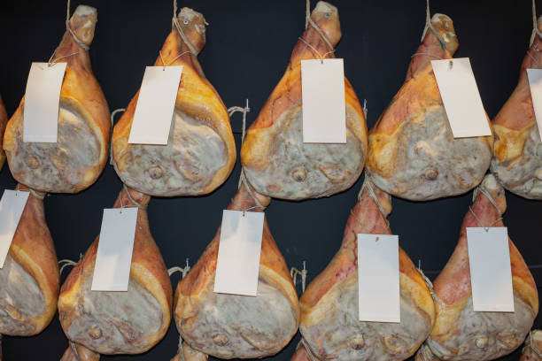 istock Group of Whole Raw Hams hung on a Wall 1354852505