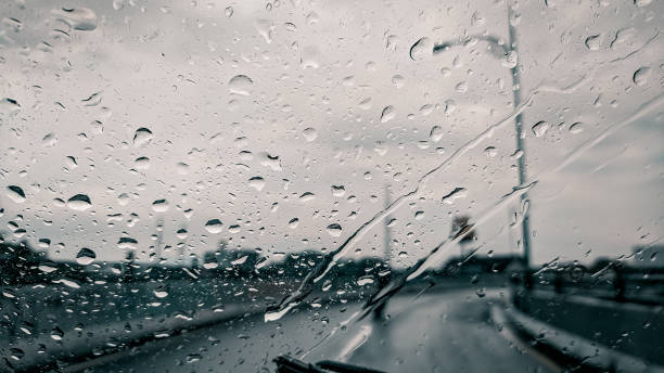 istock Raindrops on the windshield of a car on asphalt road background 1354852515