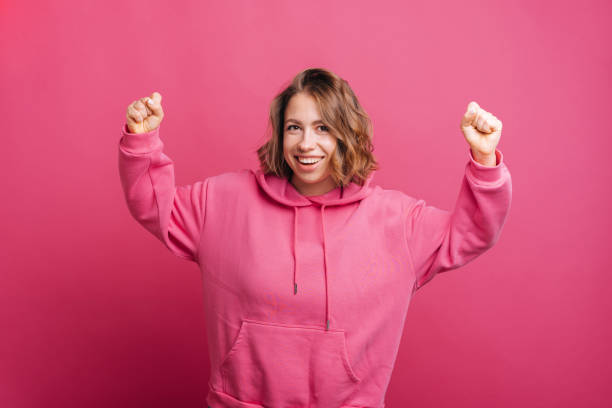 istock A joyful young woman is holding both hand up while smiling at the camera and celebrating 1354853115