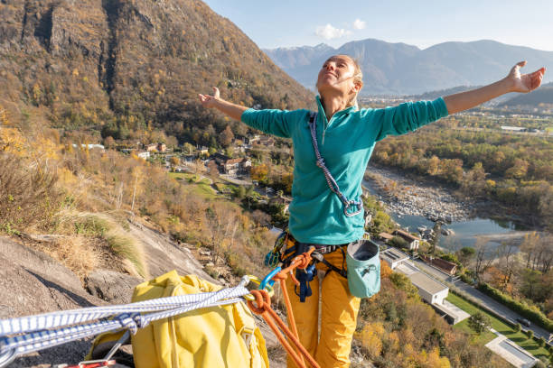 female mountain climber arms outstretched on mountain top - conquering adversity wilderness area aspirations achievement imagens e fotografias de stock