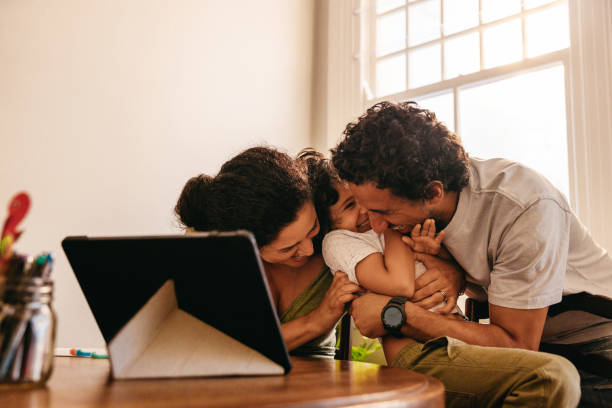 istock Cheerful parents tickling their son at home 1354854357