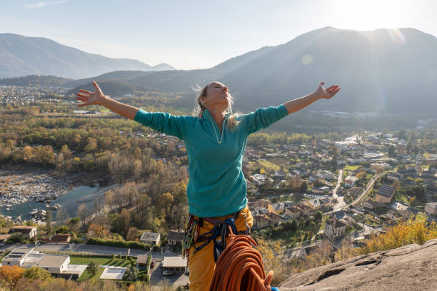istock Female mountain climber arms outstretched on mountain top 1354854528