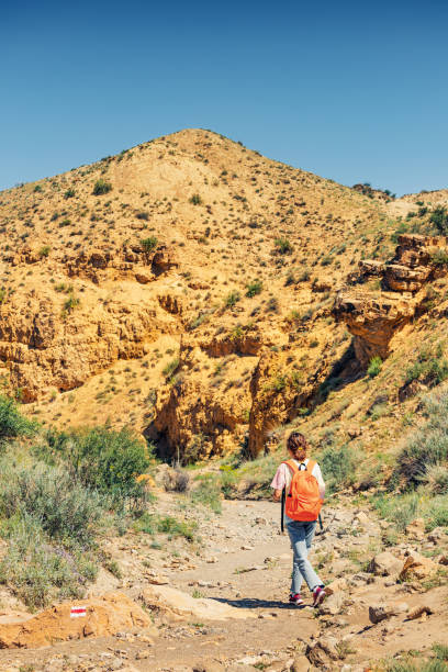 istock A woman with a backpack walks along a trail in a deserted canyon with red rocks. Hiking path and the dangers of solo trekking 1354854792