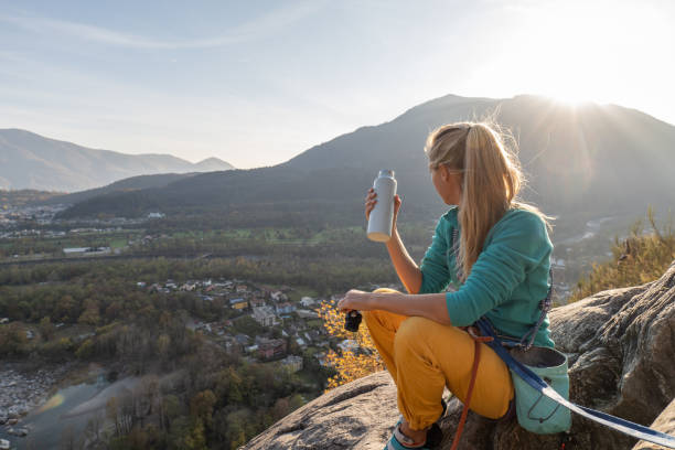 l'arrampicata su roccia femminile si prende un momento per godersi il panorama - climbing clambering hanging rope foto e immagini stock