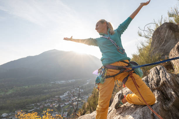 female mountain climber arms outstretched on mountain top - conquering adversity wilderness area aspirations achievement imagens e fotografias de stock