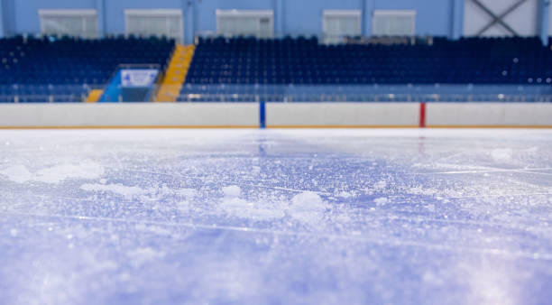 Empty stands of the ice arena and clean ice cut by skates. Clean empty ice hockey rink. Skate blade marks and snow crumbs. Empty stands in background. ice rink stock pictures, royalty-free photos & images